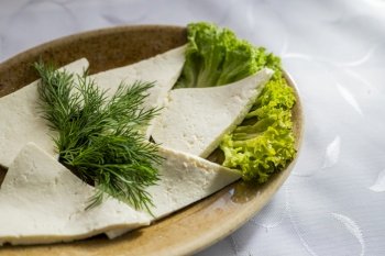 a dish of sliced ??cheese feta cheese with dill