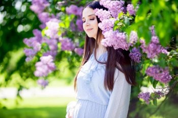 A beautiful girl stands drowning in a flowering lilac bush 
