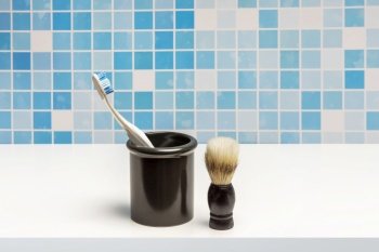 Gray coarse china mug with a toothbrush next to a brush for applying soap to the face