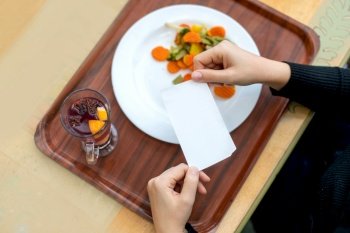 A tray with healthy food and tea. Receipt for an order in a cafe. Women’s hands hold the receipt over a tray with a plate and fruit tea.