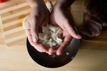 Men’s hands pour onion pieces into the dishes. Men’s hands hold pieces of onion near the bowl