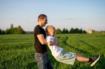sitting next to a child, sitting on the grass, studying, dad, son, child, father, upbringing, development, interest, watching, playing, family vacation, nature walk, spring, reaching for flowers, blooming tree. Dad took his happy son in his arms and they laugh