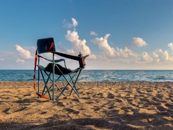 Folding camping chair facing the sea on the beach in the evening in autumn