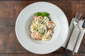 different types of pelmeni or russian dumplings in white plate on wooden background