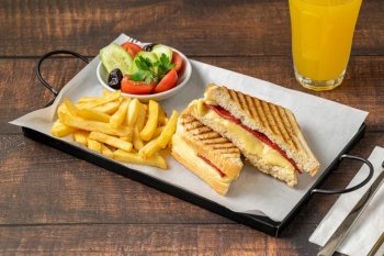 Toast with cheddar cheese and turkish sausage with french fries and salad on wooden table