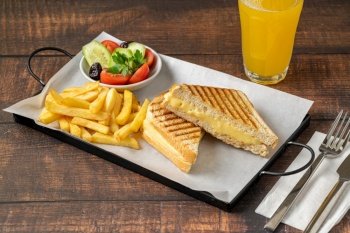 Cheddar cheese toast with french fries and salad on wooden table