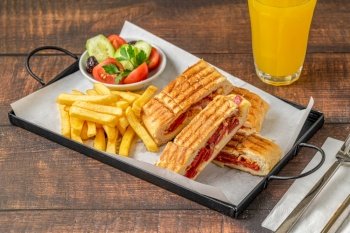 Toast with cheddar cheese and turkish sausage with french fries and salad on wooden table