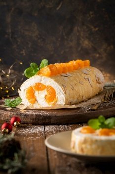 Meringue roll cake with cream, tangerine. Roulade, christmas dessert served in ceramic plate. Pavlova sweet dessert.