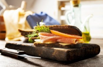 Sandwich with tasty ham on wooden board