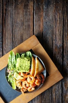Healthy appetizer or snack avocado shrimp bruschetta. Fried shrimp and mashed avocado on black plate. Healthy appetizer or snack avocado shrimp bruschetta. Fried shrimp and mashed avocado on plate for breakfast