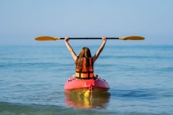 woman in life jacket paddling a kayak boat in the sea