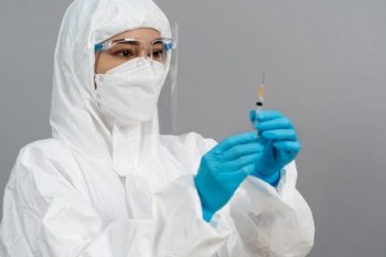 doctor in protective PPE suit holding syringe with Coronavirus (Covid-19) vaccine for injection test