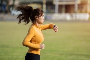 young woman running and looking at her smart wrist watch in the park