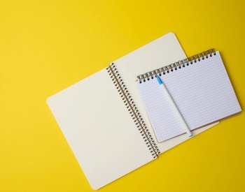 open notebook in a cage with white blank sheet and on a yellow background, top view
