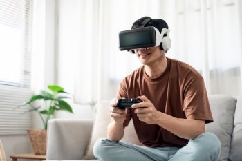 Technology Concept A person wearing a virtual reality headset and holding a black console game while sitting on the sofa.