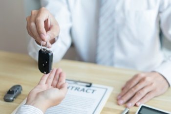 Insurance concept the customer receiving the car key after finishing the contract of car purchasing.