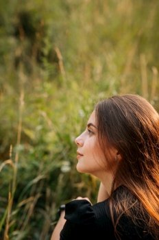 Summer photo of a girl on the background of a grass meadow.. The beauty sits in the summer among the grass in the meadow 3661.