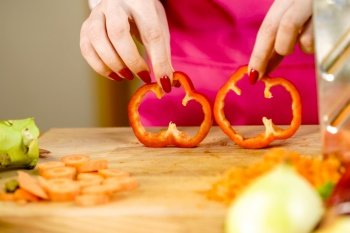 Cooking woman showing two red bell pepper paprika rings, sliced healthy vegetable, salad ingredient.. Woman showing sliced red bell pepper rings