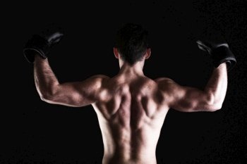 Boxer raising his arms strong athletic muscle man, sports guy showing his muscles male back isolated on black background
