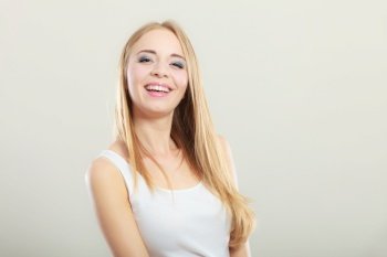 Portrait of young beautiful blonde woman smiling on gray background