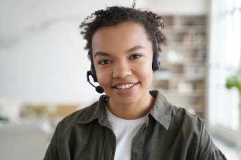 Smiling biracial young female student in headset with microphone learning foreign language online, friendly african american teen girl in headphones looking at camera. Distance education, e-learning.. Biracial girl student in headset learning online, looking at camera. Distance education, elearning