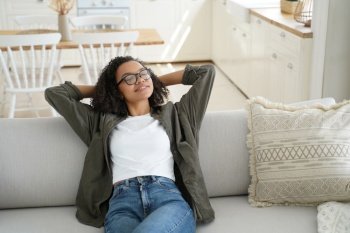 Lazy weekend morning. Attractive african american girl is relaxing on couch at home. Young woman is stretching, smiling and dreaming. Comfort and cosy home concept. Scandinavian interior.. Lazy weekend morning. Attractive african american girl is relaxing at home and smiling.