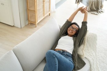 Lazy weekend morning of teenager. Carefree african american girl is relaxing on couch and pillow at her apartment. Young afro woman is stretching and smiling. Leisure and rest concept.. Carefree african american girl is relaxing on couch and pillow at her apartment. Leisure concept.