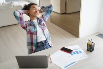 Calm relaxed biracial female student relaxes, dreams at desk, takes break from laptop computer work. Young teen girl sit on workplace with closed eyes, rest after learning, putting hands behind head.. Biracial girl student relax enjoying break from laptop work at desk after learning at home