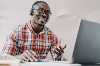 Friendly manager of client support service. African american man in headset receives calls. Online shop assistant is working from home. Teacher has remote lesson. Student gets distant education.. Friendly manager of client support service. African american man in headset receives calls.