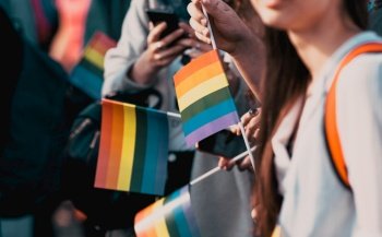 crowd waving rainbow flags at pride parade