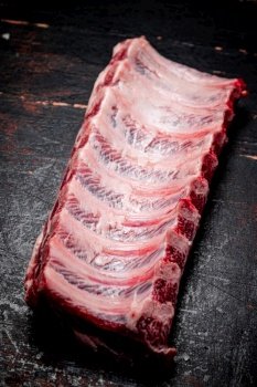 Fresh raw ribs on the table. On a rustic dark background. High quality photo. Fresh raw ribs on the table. 