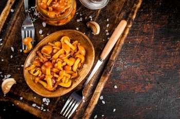 Marinated mushrooms on a wooden plate. On a rustic dark background. High quality photo. Marinated mushrooms on a wooden plate. 