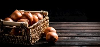 A full basket of onions on the table. On a wooden background. High quality photo. A full basket of onions on the table. 