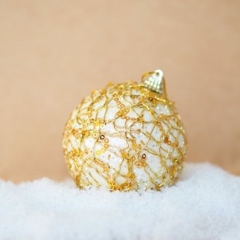 golden Christmas ball on a snowdrift on a craft background.
