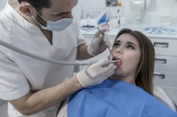 A Dentist examining little boy’s teeth in clinic