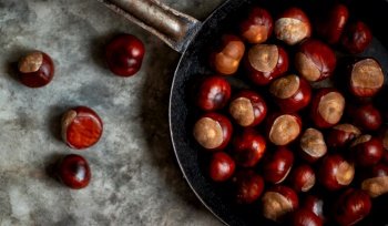 Ripe chestnuts on an old iron pan on the table.. Ripe chestnuts in an old iron pan.
