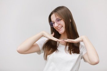 pretty teenage girl in glasses having fun on a white background. female in white t shirt with long hair in studio.. pretty teenage girl in glasses having fun on a white background. female in white t shirt with long hair in studio