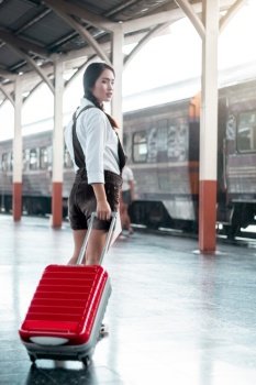 Asian woman pregnant travel carrying her trolley red bag and map in railway station travel,Holiday travel concept