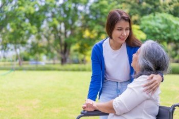 Asian careful caregiver or nurse hold the patient hand and encourage the patient in a wheelchair. Concept of happy retirement with care from a caregiver and Savings and senior health insurance.