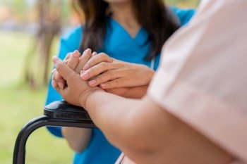 Asian careful caregiver or nurse hold the patient hand and encourage the patient in a wheelchair.  Concept of happy retirement with care from a caregiver and Savings and senior health insurance.