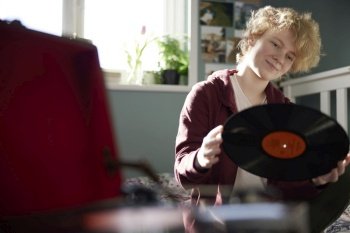 Teenage Girl Playing Vinyl Records On Record Player At Home In Bedroom