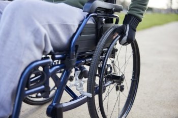 Close Up Of Teenage Boy Wearing Protective Gloves In Wheelchair In Park