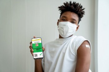 African American teenager shows vaccine passport on mobile phone to validate travel permission by the digital document. Vaccine Passport V5