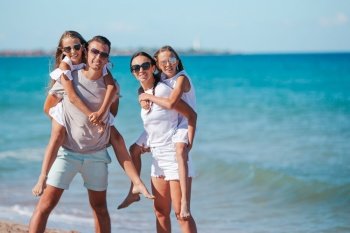 Parents with two kids have fun on the beach. Young family on vacation have a lot of fun