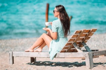 Beautiful woman relax during exotic vacation on the beach enjoying sweet coffee. Young woman with cup of hot coffee enjoy holidays