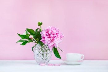 A cup of tea and peonies in a vase. A cup of tea and peonies
