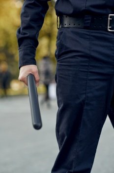 Male police officer in uniform holds baton. Policeman protect the law. Cop works on city street, order and justice control. Male police officer in uniform holds baton