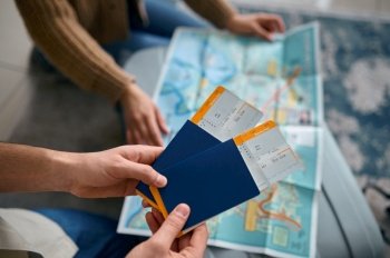 Closeup travel ticket boarding pass in hand over guide map. Family couple preparing for vacation. Closeup ticket in hand over guide map