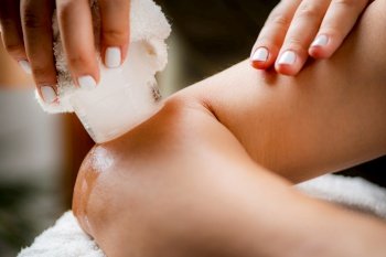 Ice Massage for Painful Elbow. Hands of a therapist placing ice directly onto a painful elbow to relieve pain, reduce inflammation and swelling and promote healing.. Ice Massage for Painful Elbow.