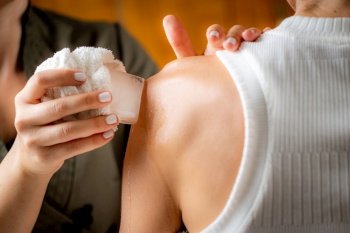 Shoulder cryotherapy ice massage. Hands of a therapist placing ice directly onto a painful shoulder to relieve pain, reduce inflammation and swelling and promote healing.. Shoulder Cryotherapy Ice Massage.